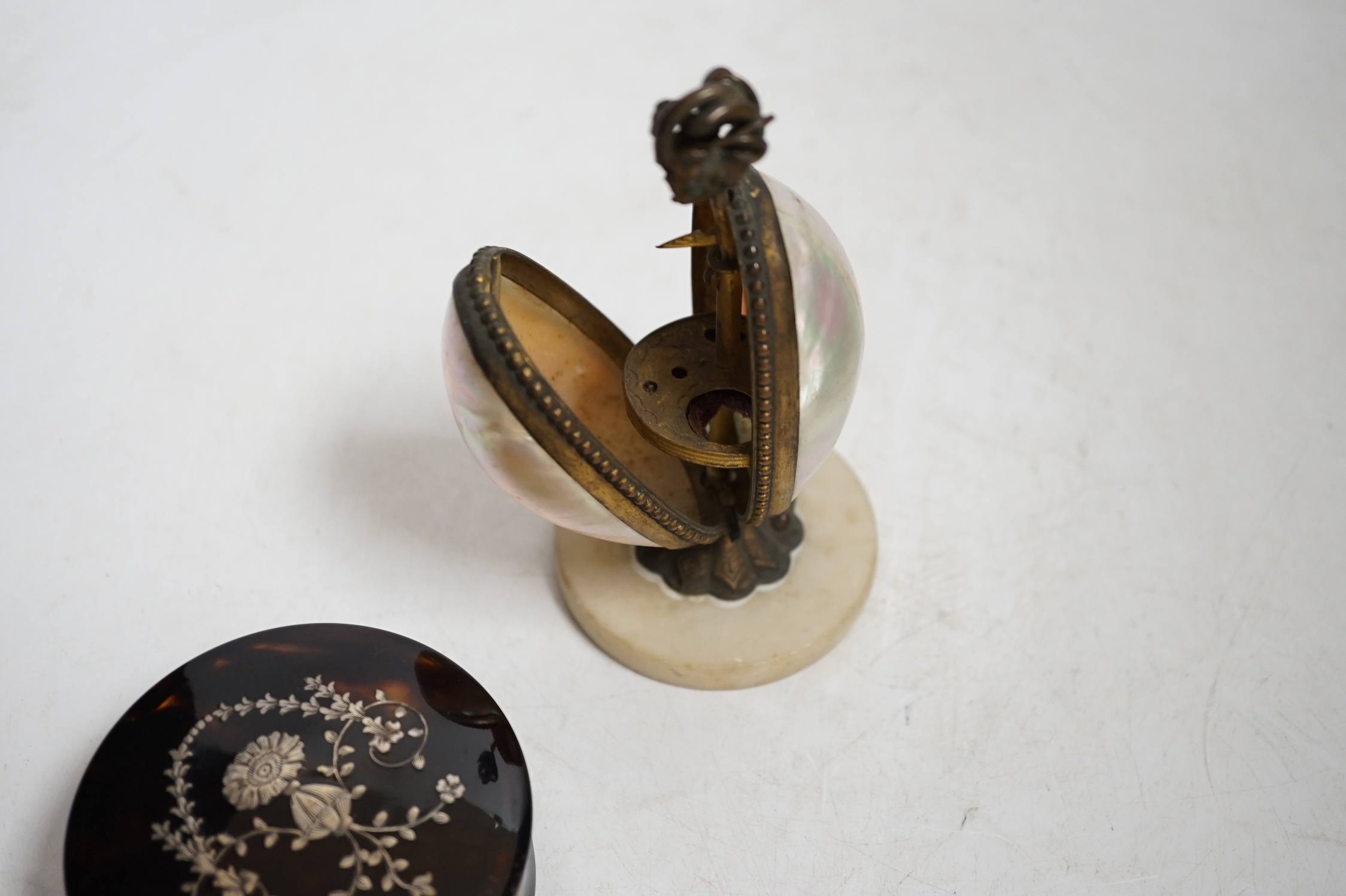 A Victorian tortoiseshell and silver piqué inlaid circular lidded snuff box and a Palais Royale mother-of-pearl and ormolu needlework case, largest 13cm high. Condition - fair, case does not snap shut